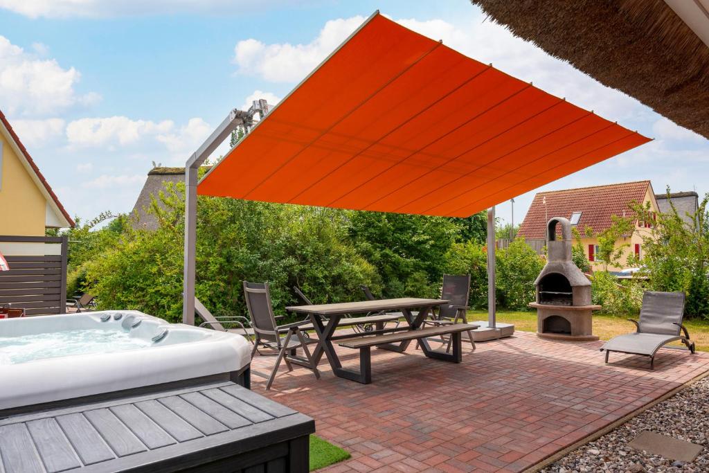 B 4 Reethaus Jaguar mit Sauna und Whirlpool في Gramkow: فناء مع حوض استحمام ساخن وطاولة وطاولة نزهة مع مقعد