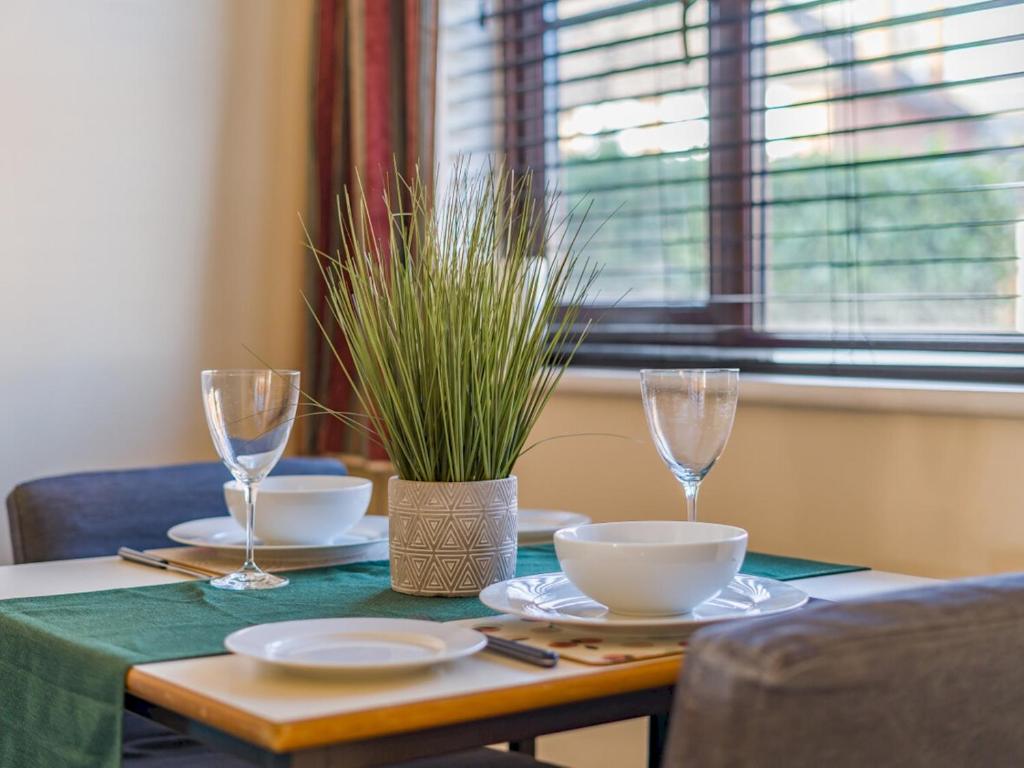 a table with plates and glasses and a plant on it at Hersham Apartment Ideal for Work & Relaxation - Pass the Keys in Hersham