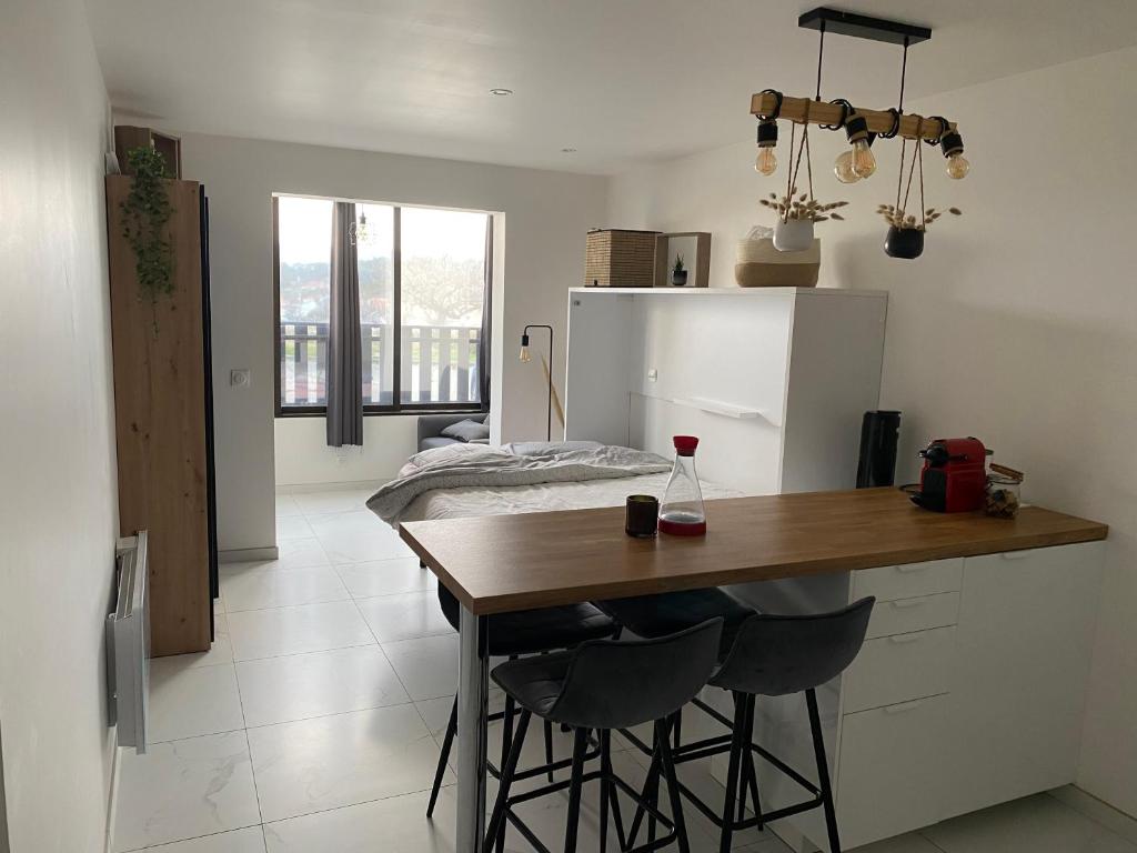 - une cuisine avec une table en bois et deux tabourets de bar dans l'établissement Studio Côte & Vague - Votre parenthèse océan à Lacanau, à Lacanau