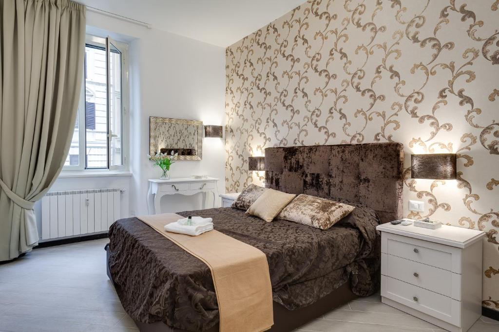 ローマにあるPrime Vatican Suitesの大型ベッドと壁紙を用いたベッドルーム1室が備わります。