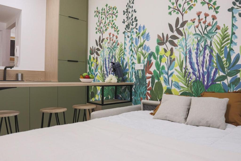 - une chambre avec un lit blanc et un mur fleuri dans l'établissement Jardin enchanté, city center, à Mulhouse