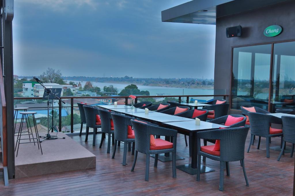 a restaurant with tables and chairs on a balcony at Amanta Hotel Nongkhai in Nong Khai