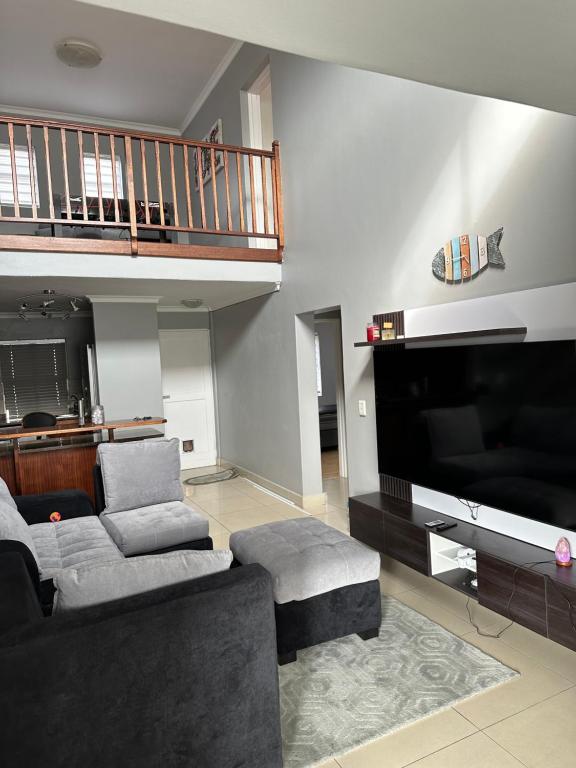 a living room with a couch and a flat screen tv at YA Eagle Wings Self Catering Shared Single room Apt B in Cape Town