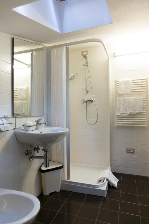 a white bathroom with a shower and a sink at Hotel Miramare in Pineto