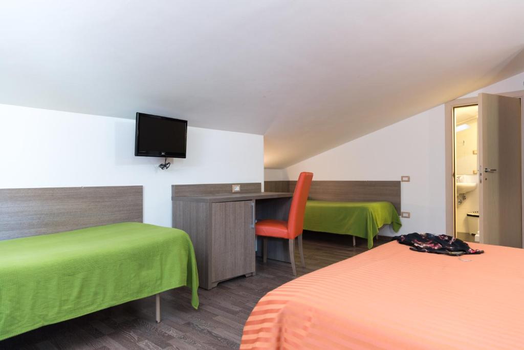 a room with two beds and a desk with a television at Hotel Miramare in Pineto