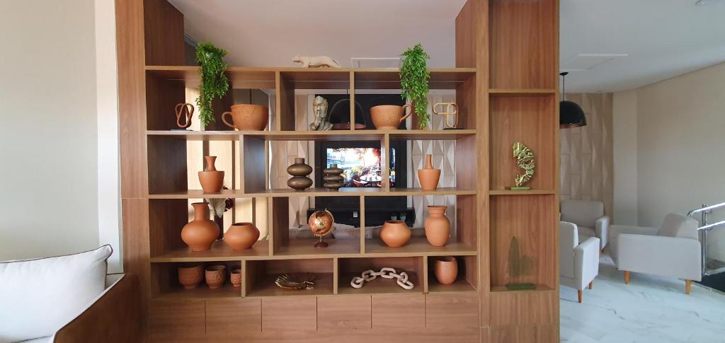 a wooden book shelf with vases and plants on it at Nordeste Palace Hotel - Glória-SE in Nossa Senhora da Glória