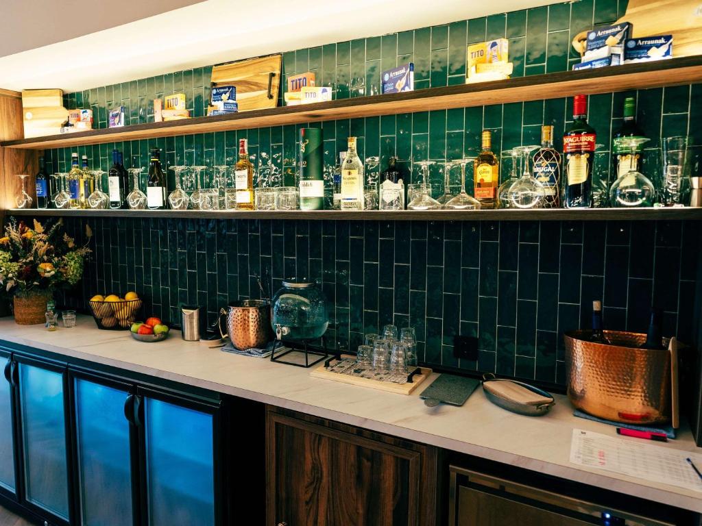 bar z wyłożoną zielonymi kafelkami ścianą z butelkami i kieliszkami w obiekcie Ibis Styles Madrid Centro Maravillas w Madrycie