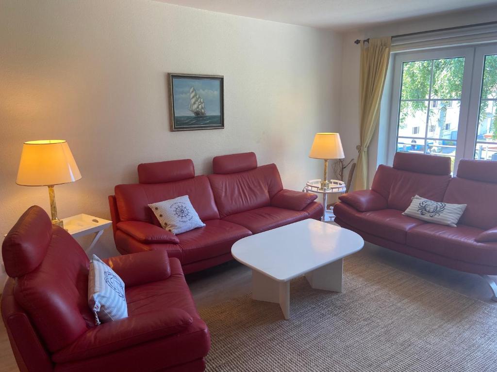 ein Wohnzimmer mit roten Sofas und einem weißen Tisch in der Unterkunft Meeresrauschen - a57320 in Zingst