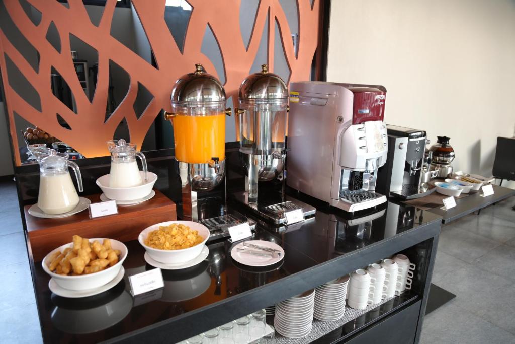 a counter with a coffee maker and bowls of food at Amanta Hotel Nongkhai in Nong Khai