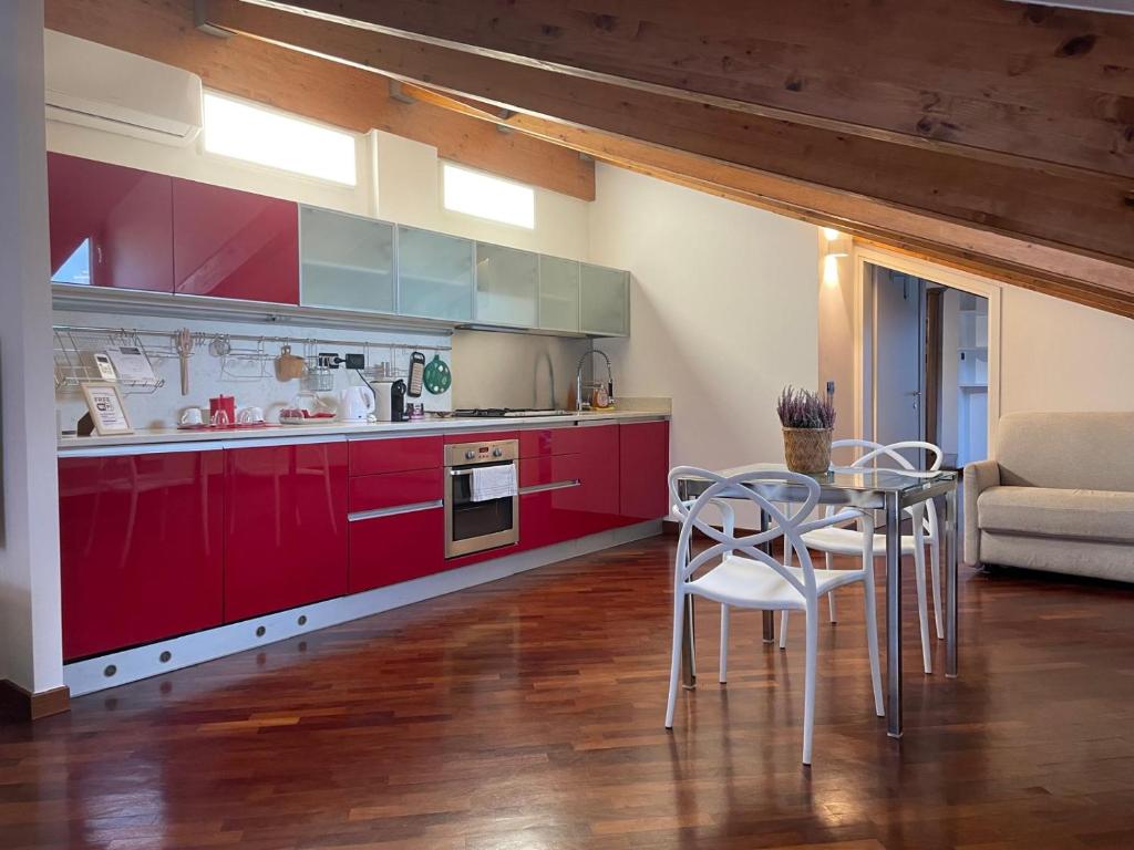 a kitchen with red cabinets and a table and chairs at La Mansarda di Pinocchio e dei Lego in Bologna