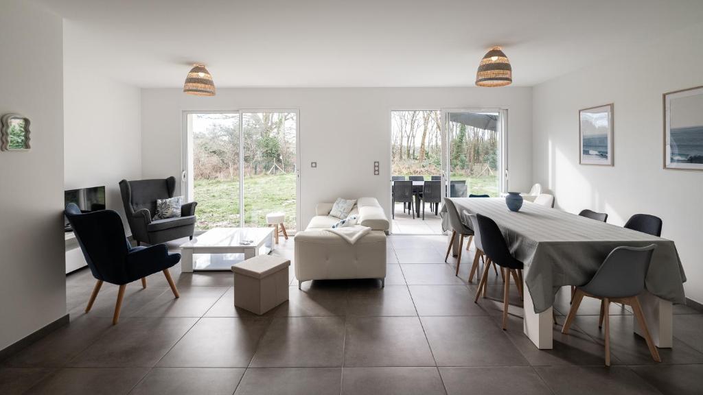 un salon blanc avec une table et des chaises dans l'établissement La Maison aux Chevreuils, à Parentis-en-Born
