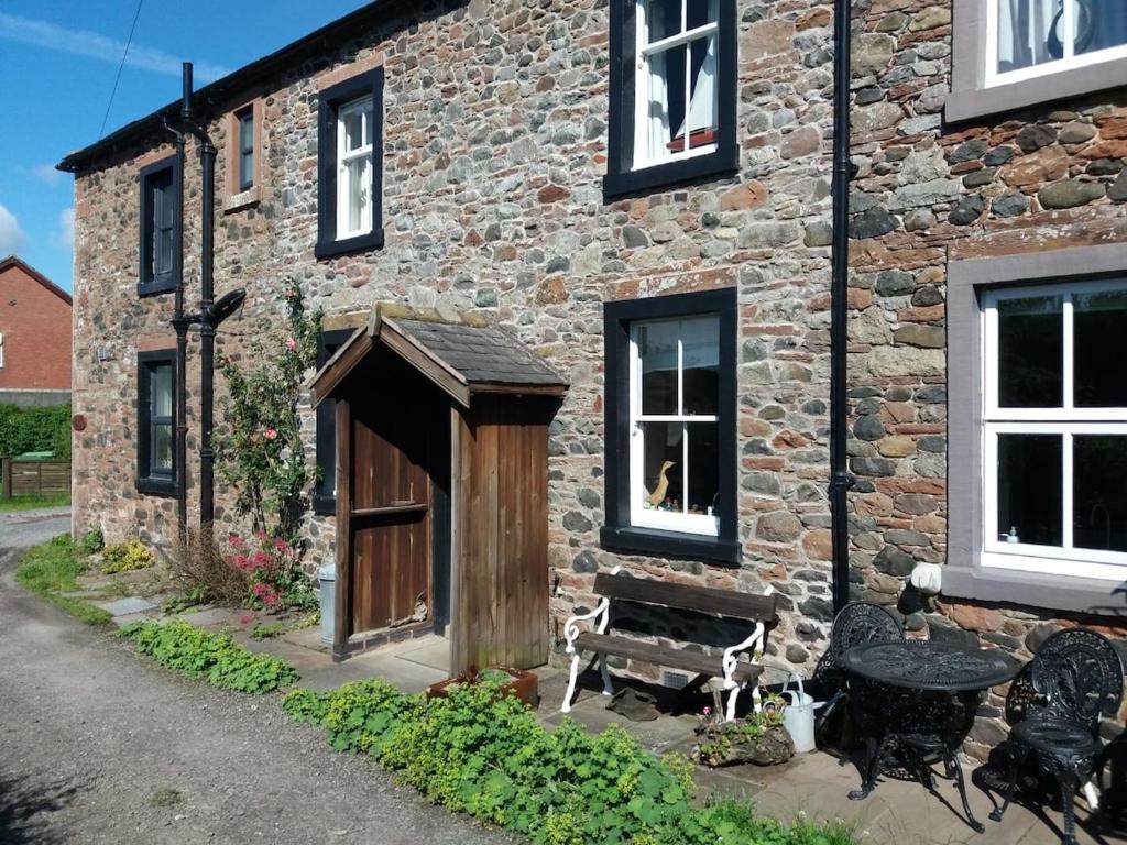 a brick building with a door and a bench outside at Rose cottage on the peaceful solway coast in Port Carlisle