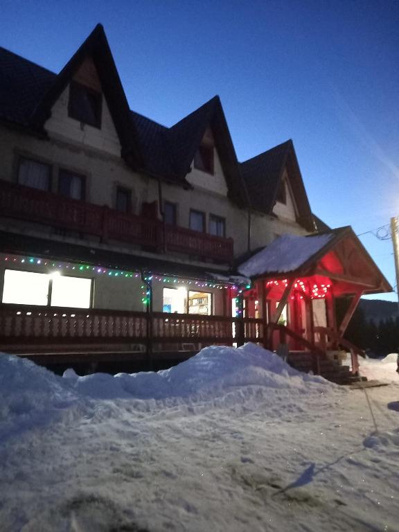 a building with christmas lights in the snow at Gentiana-Sureanu in Tău Bistra