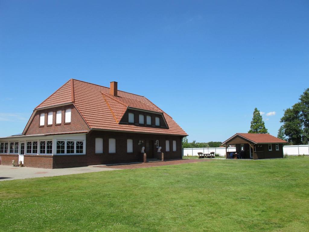 un gran edificio con un campo de hierba delante de él en Ferienhaus INGE MOOR203 ruhig gelegen im Hinterland der NORDSEE, en Südbrookmerland