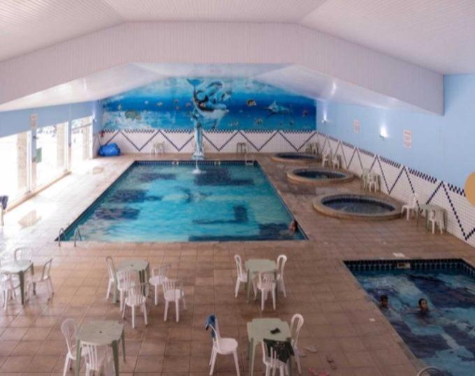 einen großen Innenpool mit Tischen und Stühlen in der Unterkunft Capivari ecoresort residence in Campina Grande do Sul