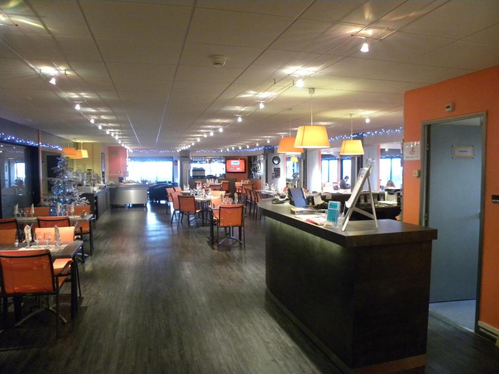 un restaurant avec un bar, des tables et des chaises dans l'établissement Hôtel De La Plage, à Calais