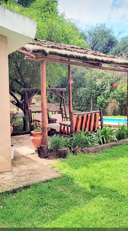 a wooden gazebo with two benches in a yard at Depto Valle del Sol,cerca GOLF CLUB VILLA ALLENDE in Mendiolaza