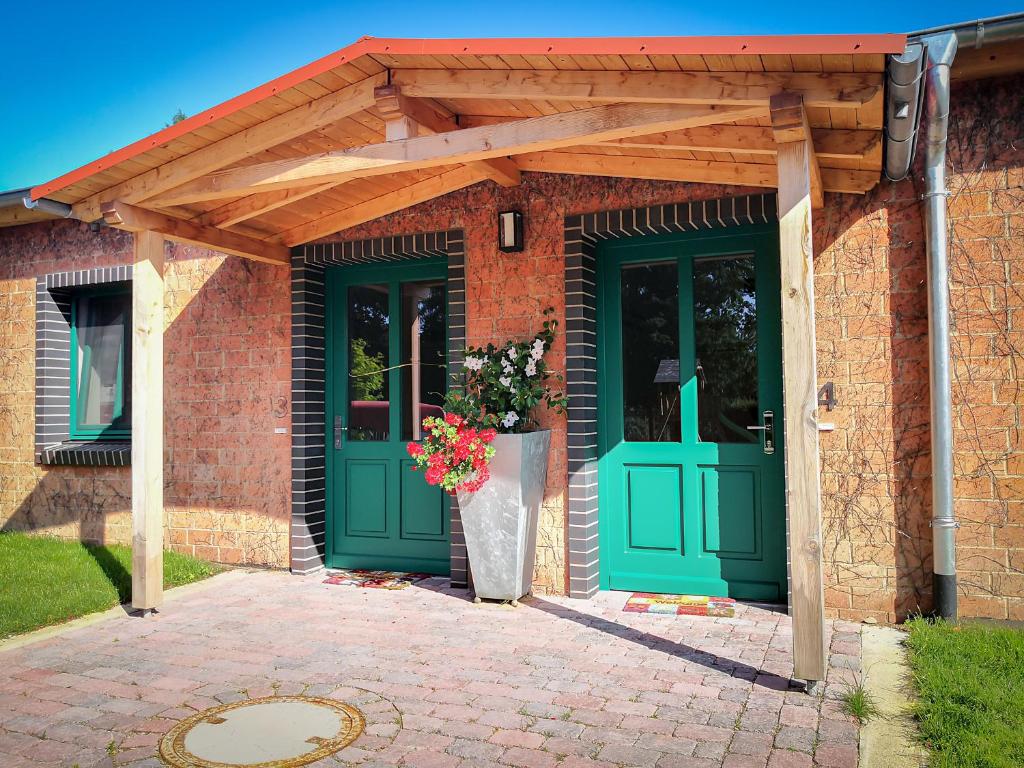 a brick house with green doors and a wooden roof at Auszeithof Otersen - Ferienwohnung 3 in Kirchlinteln