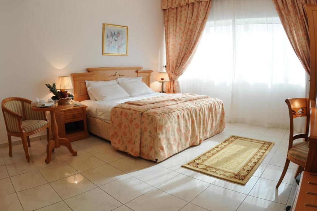 a bedroom with a bed and a table and a window at Uptown Hotel Apartments Abu Dhabi by Gewan in Abu Dhabi