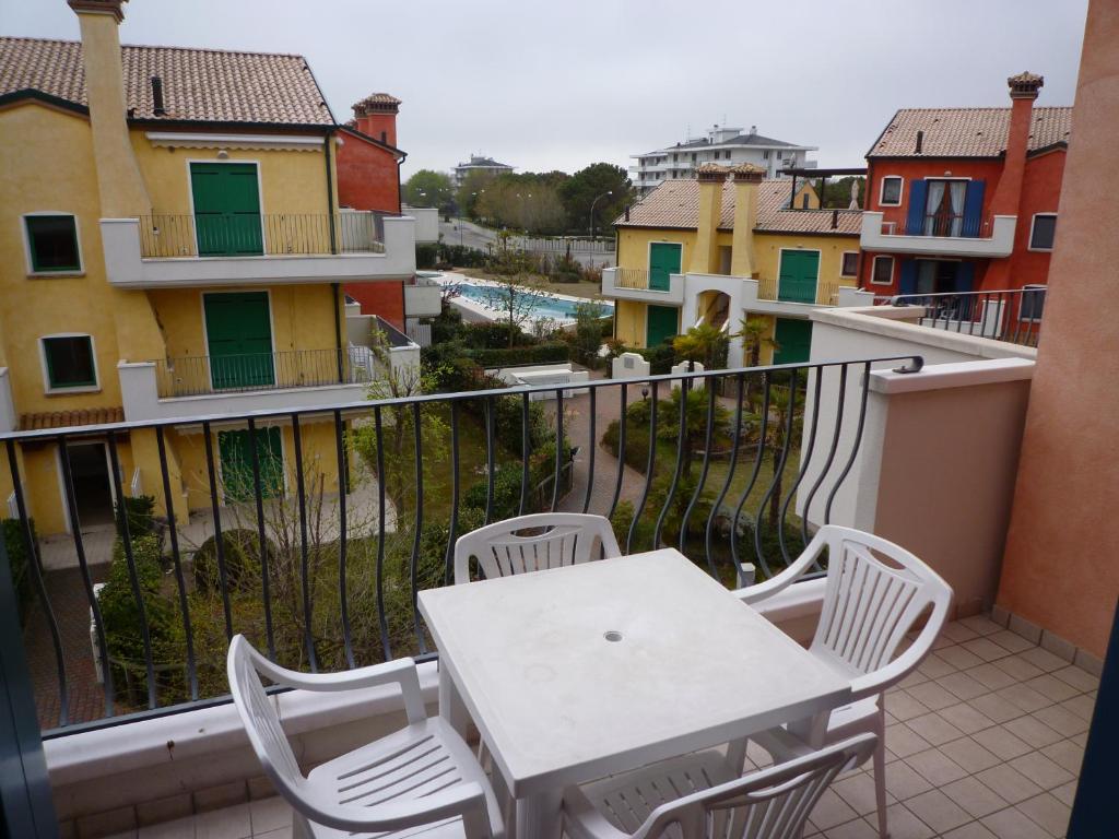 un tavolo bianco e sedie su un balcone con edifici di Le Ginestre a Cavallino-Treporti