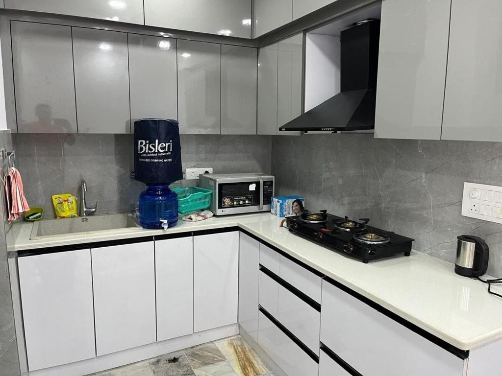 a kitchen with white cabinets and a microwave at Cozy nest 2bhk by LWB in New Delhi
