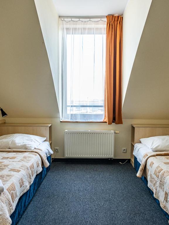 two beds in a room with a large window at Hotel Galion in Gdańsk