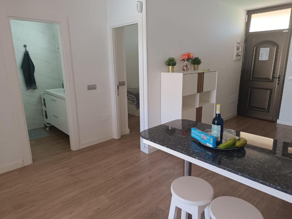 a kitchen with a table with a bottle of wine and stools at Complejo Los Cactus Apartamento Sol y Mar in Maspalomas