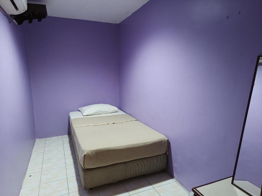 Posto letto in camera con parete viola di HOTEL MEDAN KiDD a Ipoh