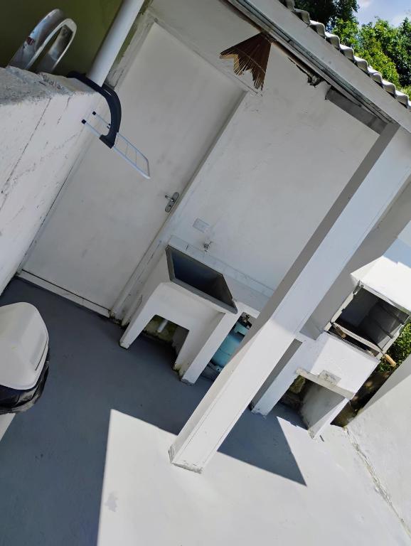 a white bench sitting on the side of a garage at Casinha no Centro in Santo Antônio do Pinhal