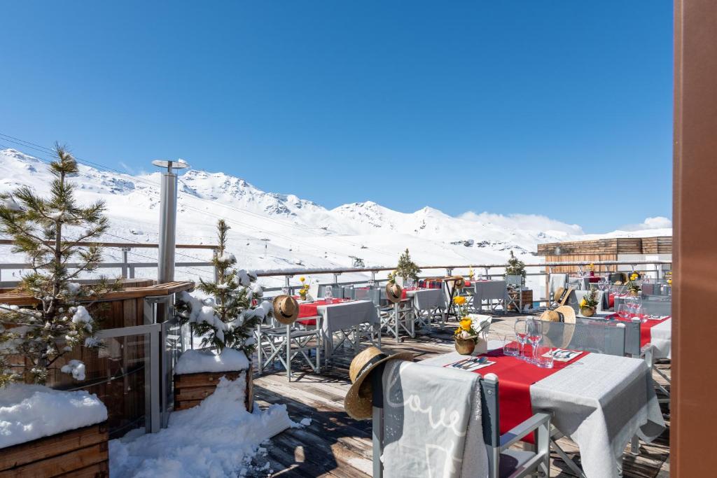 a restaurant with snow covered mountains in the background at Hotel Pashmina Le Refuge in Val Thorens