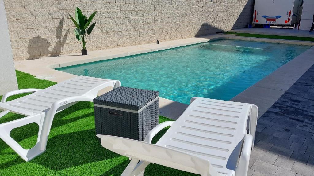 einen Pool mit zwei Gartenstühlen und einer Heizung in der Unterkunft La Casita de la Piscina in Burguillos de Toledo