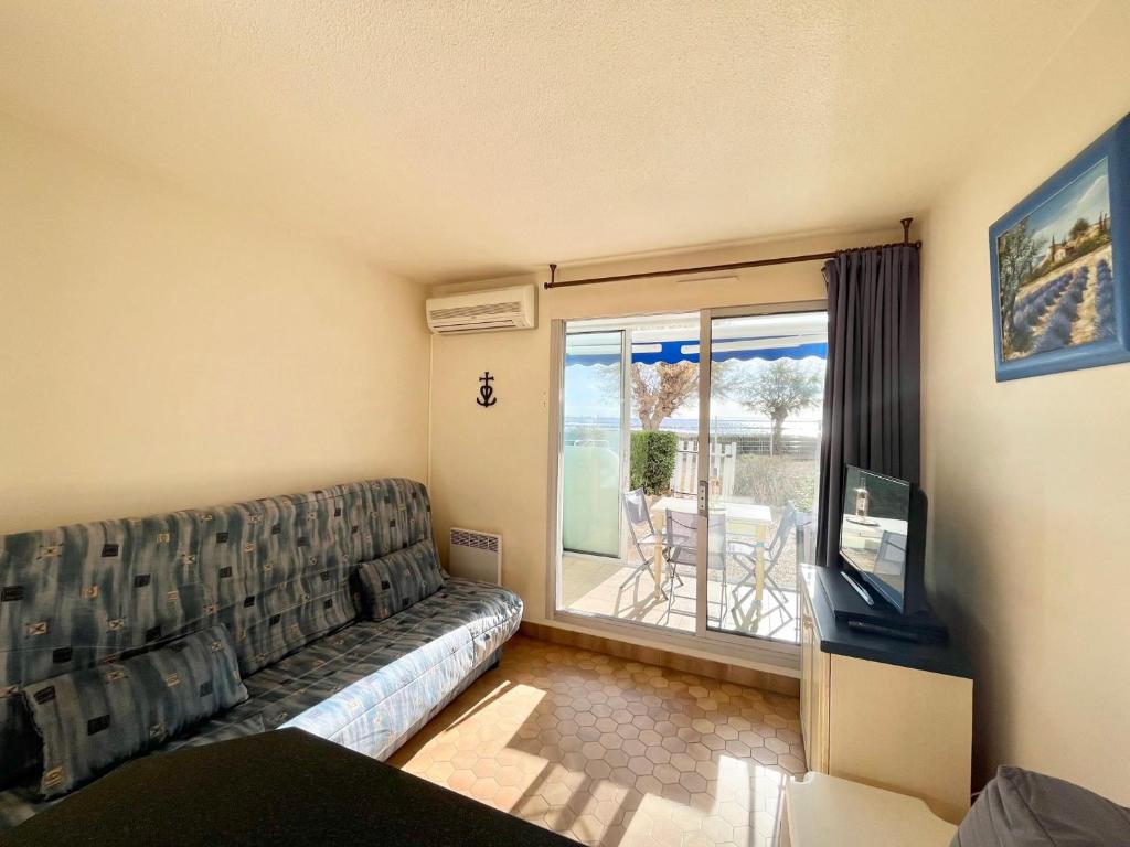 un salon avec un canapé et une télévision dans l'établissement Studio climatisé en bord de mer avec terrasse et parking privé - FR-1-716-43, à La Grande Motte
