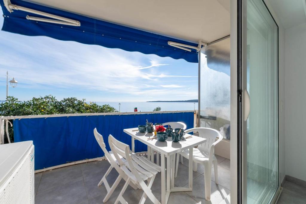 une table blanche et des chaises sur un balcon dans l'établissement 2-Br Seafront Apartment in Cannes, à Cannes