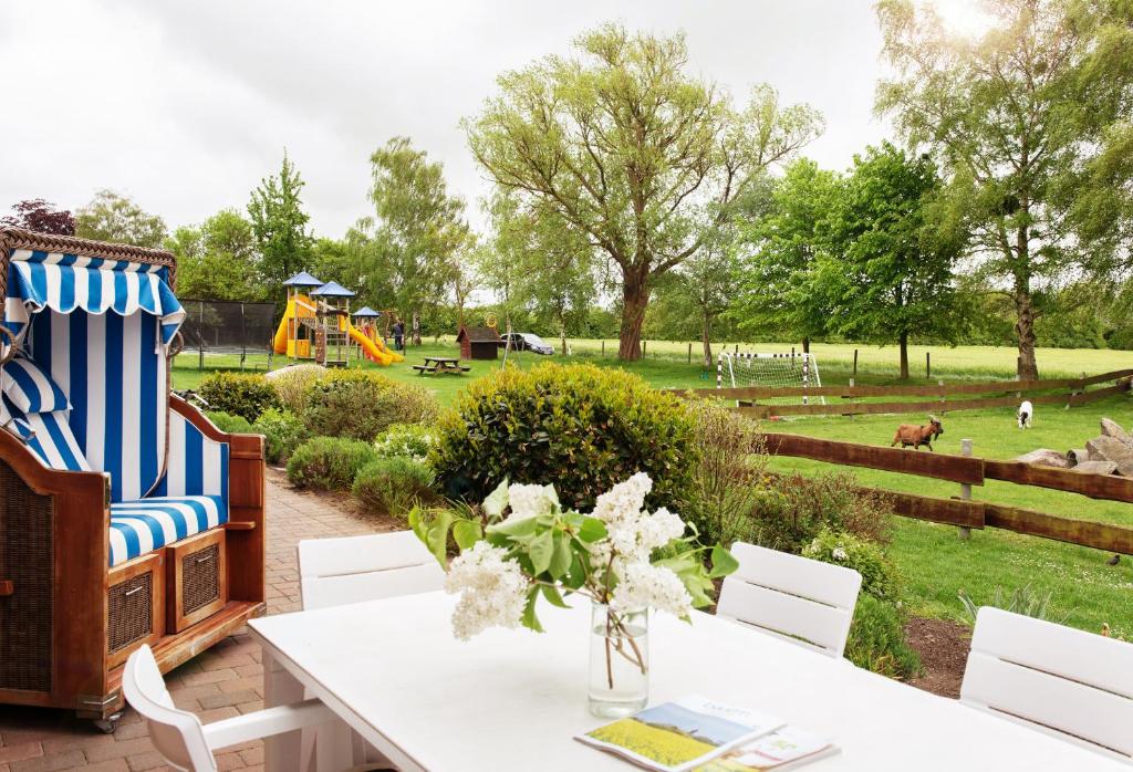 a patio with a table and chairs and a playground at Bauernhof Höper-Rauert - Nr 10 Wellnesshaushälfte in Neujellingsdorf