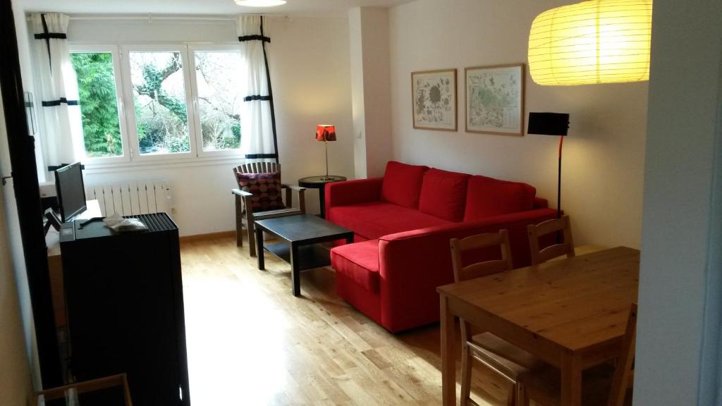 ein Wohnzimmer mit einem roten Sofa und einem Tisch in der Unterkunft Apartamentos el Camino in Villafranca del Bierzo