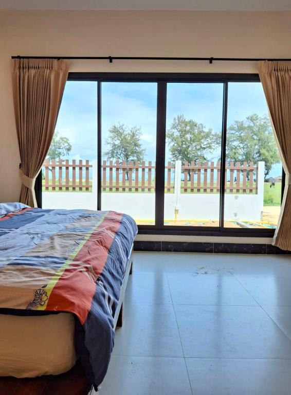 a bedroom with a bed and a large window at Mirinda Beach Resort in Ban Bo Daeng