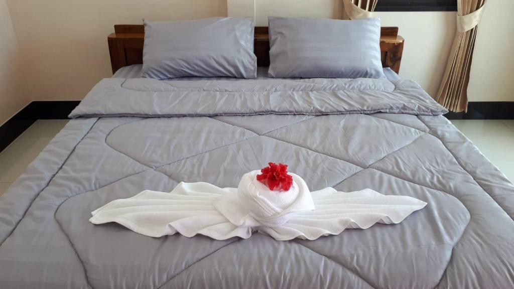 un lit blanc avec une fleur rouge dessus dans l'établissement Mirinda Beach Resort, à Ban Bo Daeng