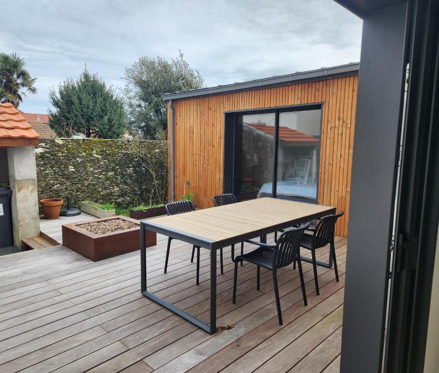 Una terraza de madera con una mesa y sillas. en L'Inattendu, en Pornic