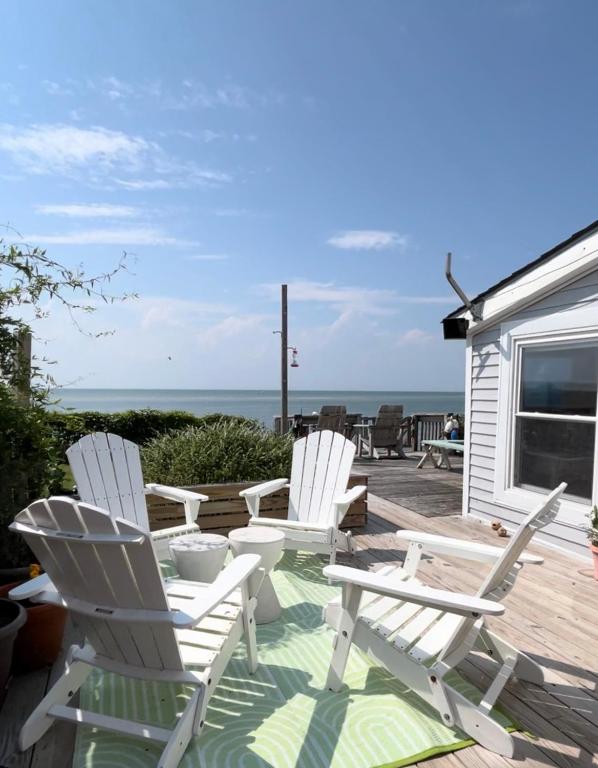 three white chairs sitting on a deck with the ocean at Beach Bettie's in Cape Charles