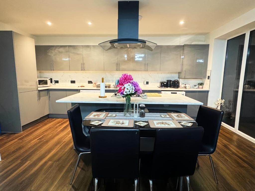 a kitchen with a table with a vase of flowers on it at Elevate your stay with Sai home in West Thurrock