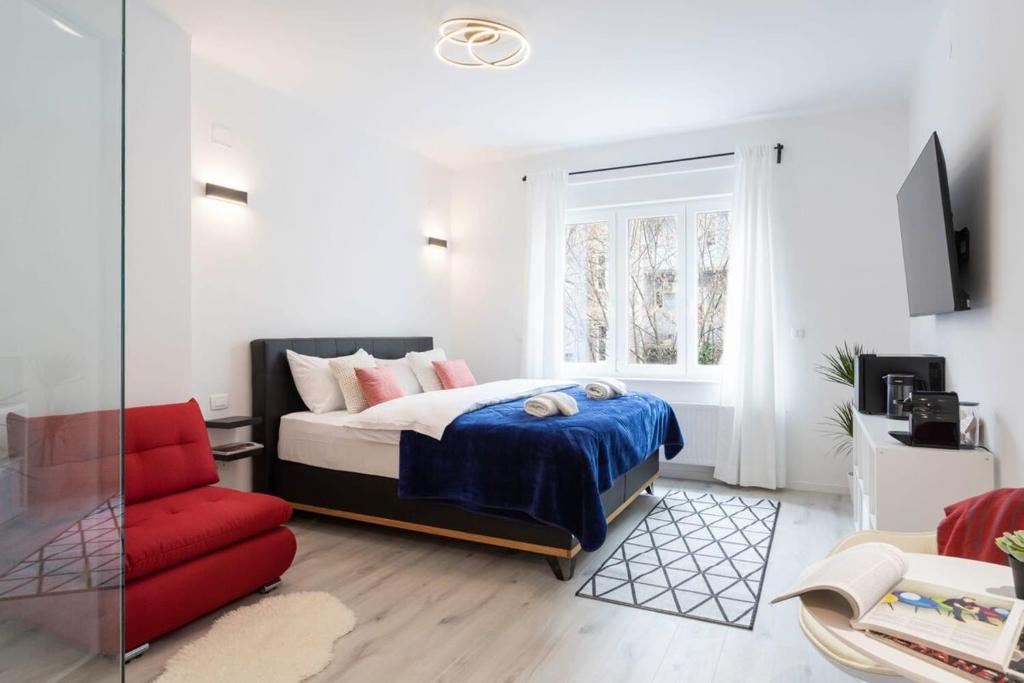 a bedroom with a bed and a red chair at Lux Nest II City Apartment URBAN STAY in Zagreb