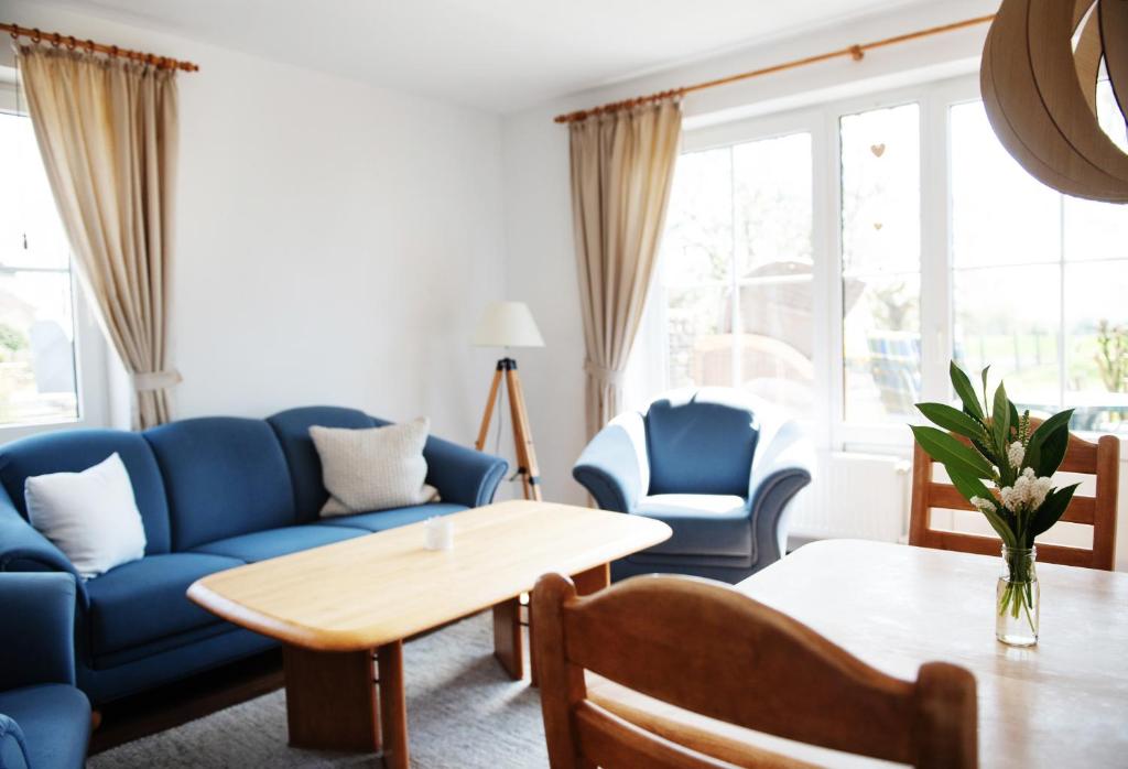 ein Wohnzimmer mit blauen Sofas und einem Tisch in der Unterkunft Bauernhof Höper-Rauert - Reihenhaus 1 in Neujellingsdorf