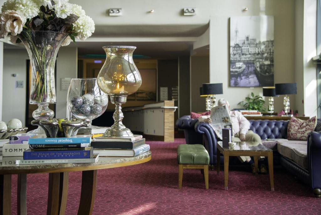 a living room with a table with a vase and books at Cork International Hotel in Cork