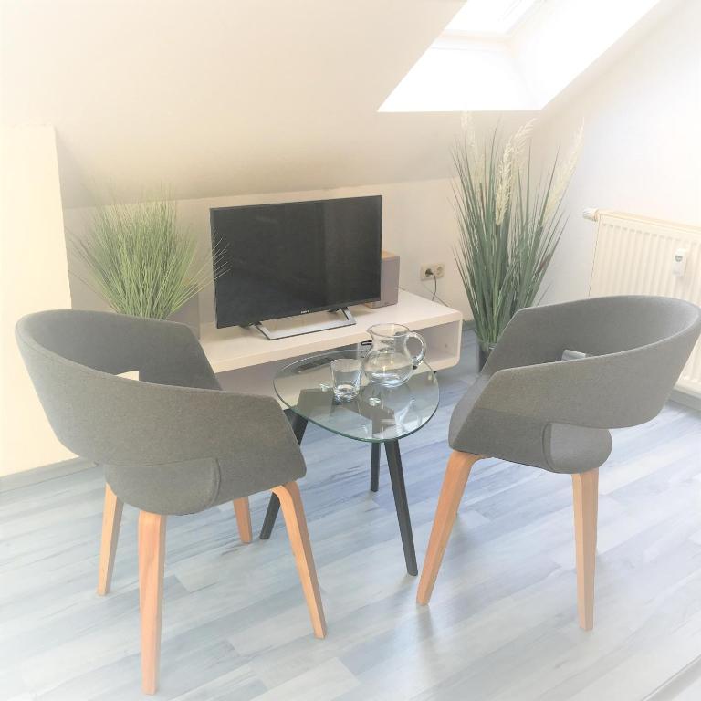 a living room with a table and two chairs and a television at App 255Haus 6 in Dierhagen