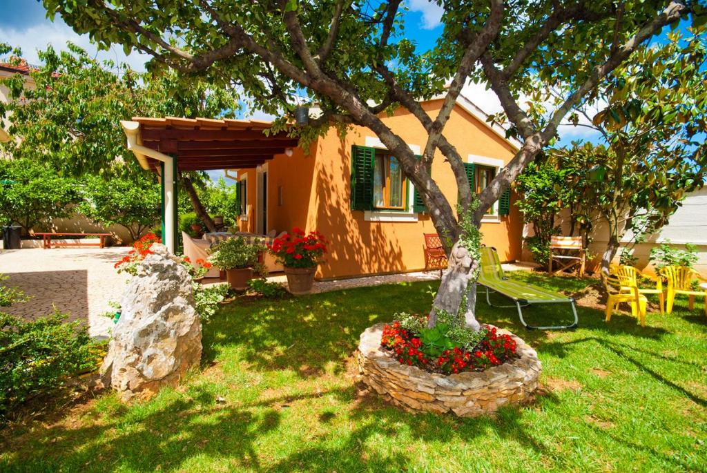 une maison avec un arbre dans une cour fleurie dans l'établissement Guest house Bizjak, à Vinkuran