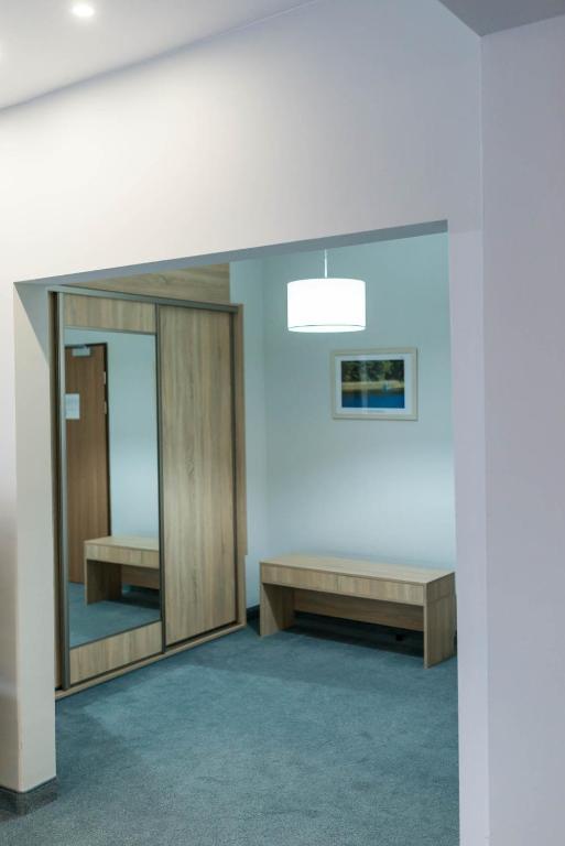 Small entry alcove with mirrored wardrobe, wooden bench, soft overhead lighting.