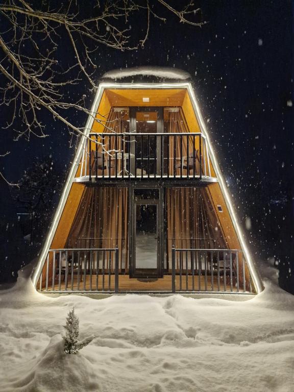 drewniany budynek w śniegu z drzewem w obiekcie Diamond Cottages w mieście Lagodekhi