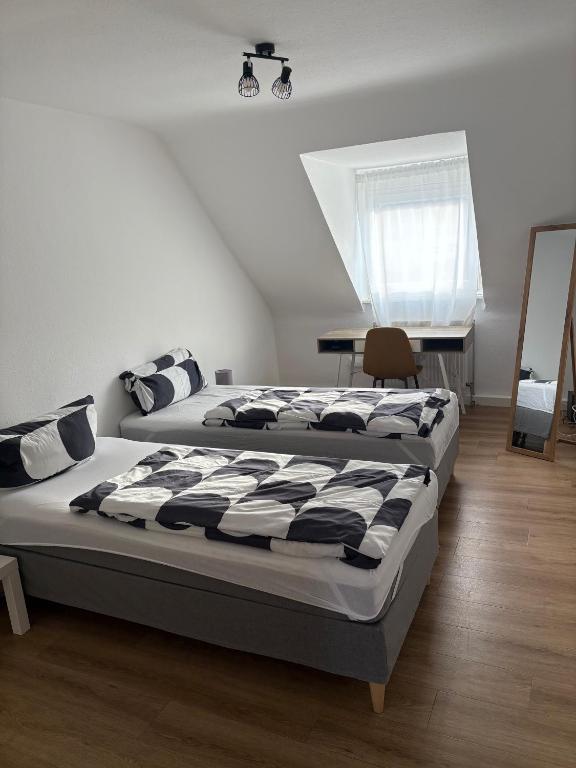 a bedroom with two beds and a desk and a window at City Nest Ettlingen - nähe Wasenpark in Ettlingen