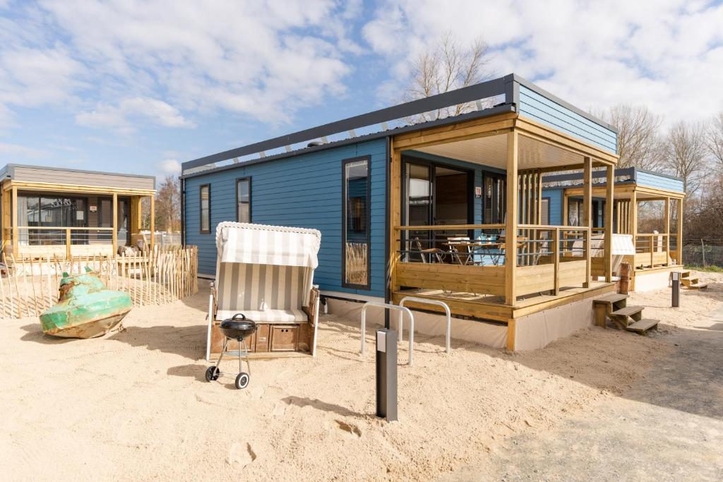 a blue tiny house with a chair in the sand at Boje 73 in Scharbeutz