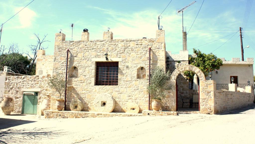 um antigo edifício de pedra com uma porta verde em Villa Fabrika em Vóroi